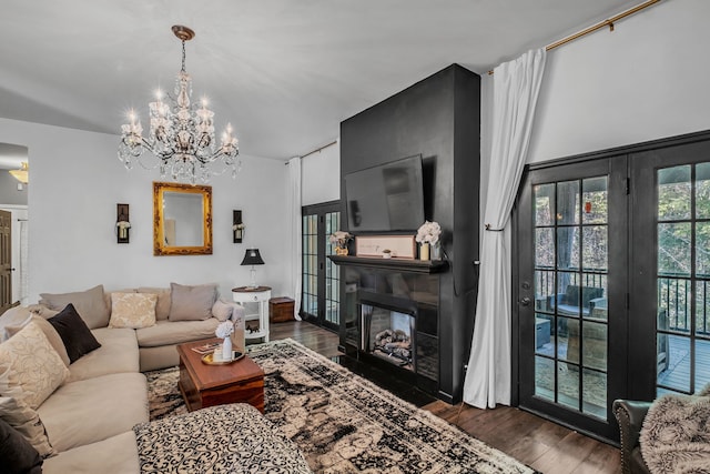 living room featuring an inviting chandelier, a large fireplace, and dark wood-type flooring