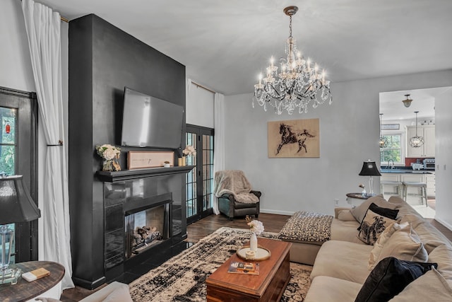 living room with a notable chandelier, dark hardwood / wood-style floors, and a fireplace