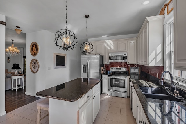 kitchen featuring dark stone counters, sink, a kitchen island, decorative backsplash, and appliances with stainless steel finishes