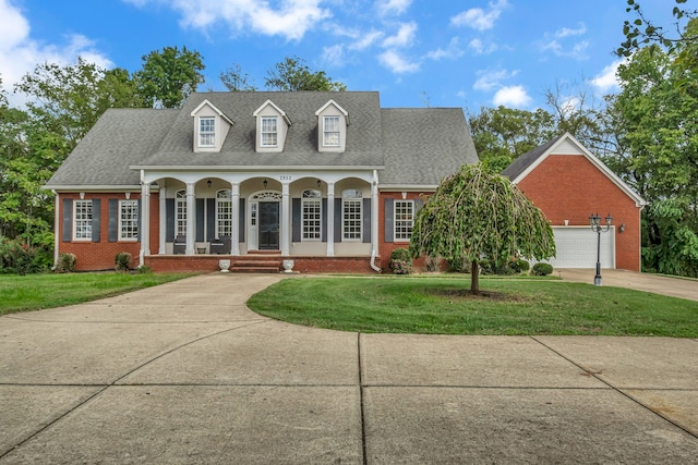 cape cod-style house with a front lawn, covered porch, and a garage