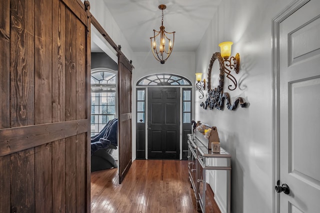 entryway featuring a barn door, hardwood / wood-style floors, and a notable chandelier