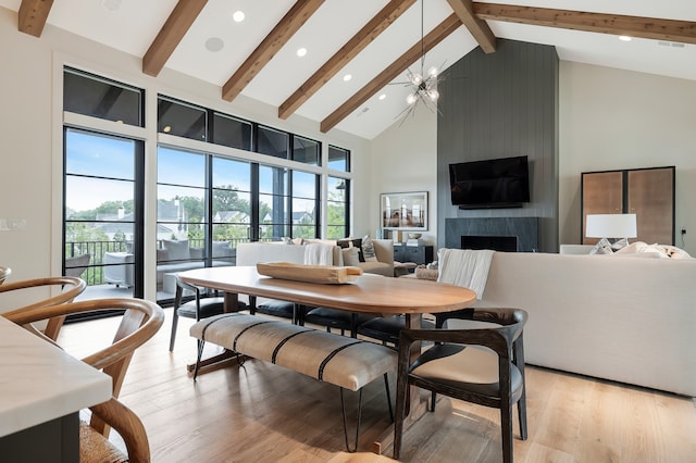 dining room with beamed ceiling, light hardwood / wood-style flooring, a premium fireplace, and high vaulted ceiling