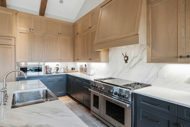 kitchen featuring gray cabinets, lofted ceiling with beams, light stone counters, custom range hood, and appliances with stainless steel finishes