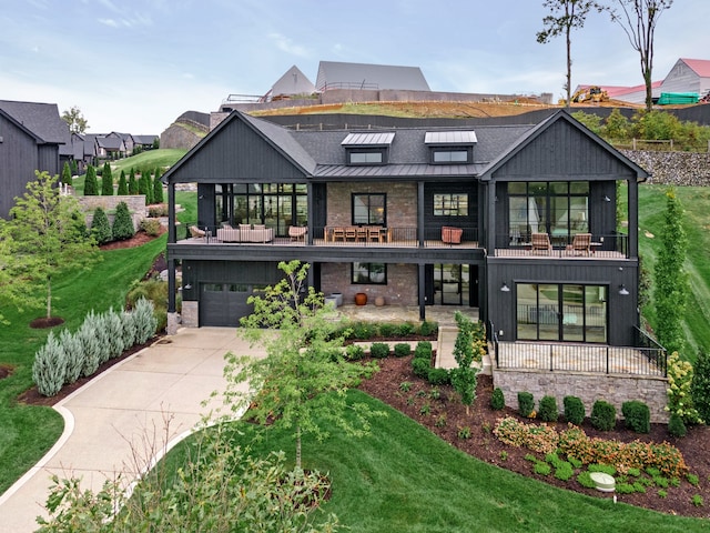 back of house with a yard, a garage, a balcony, and covered porch