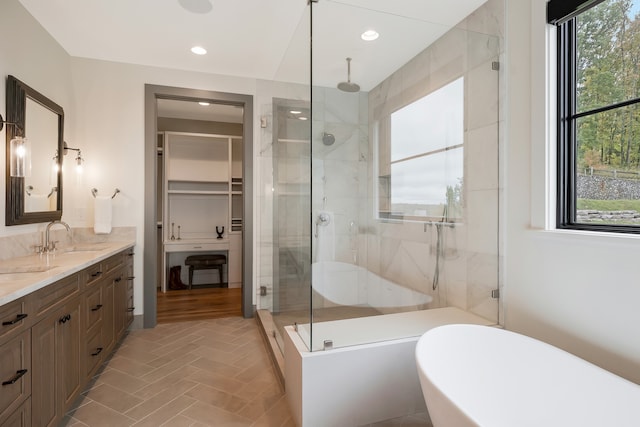 bathroom with independent shower and bath, a healthy amount of sunlight, and vanity