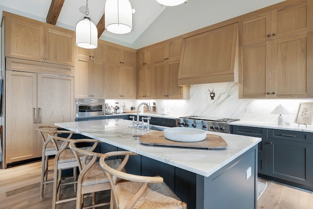 kitchen featuring lofted ceiling with beams, light stone counters, hanging light fixtures, a kitchen breakfast bar, and a center island with sink