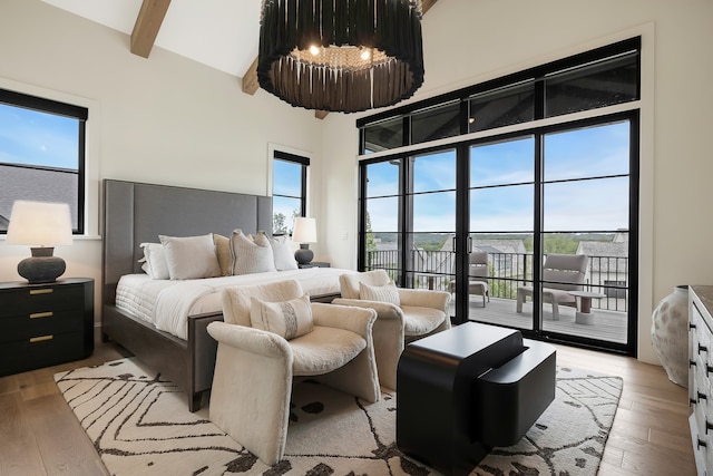 bedroom with light hardwood / wood-style floors, beamed ceiling, and access to exterior