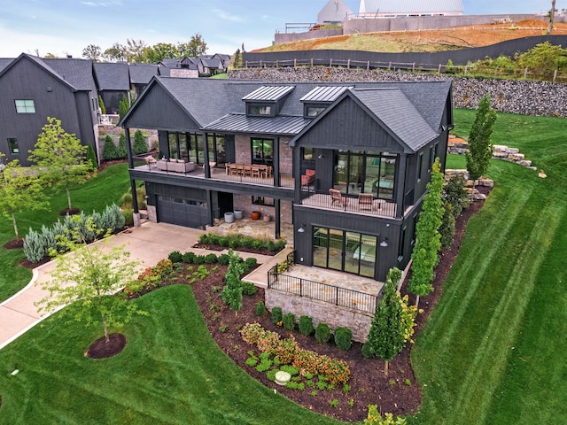 rear view of house featuring a balcony, a garage, and a lawn