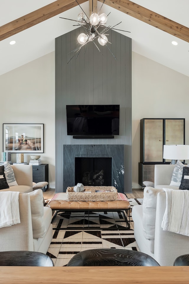 living room featuring an inviting chandelier, beamed ceiling, a premium fireplace, and high vaulted ceiling