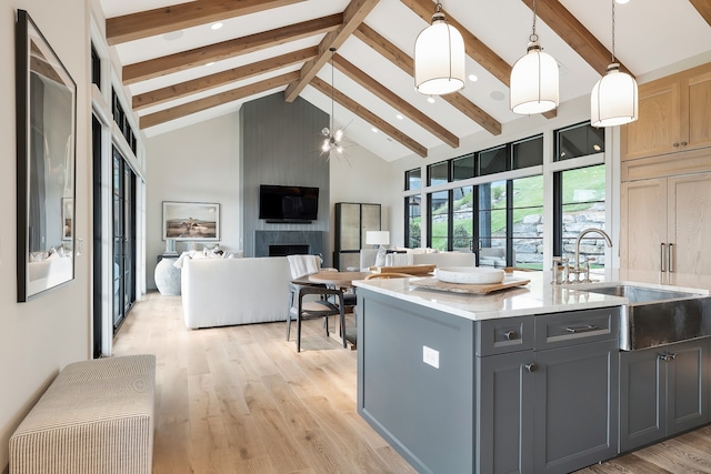 kitchen featuring high vaulted ceiling, a fireplace, beam ceiling, light hardwood / wood-style flooring, and decorative light fixtures