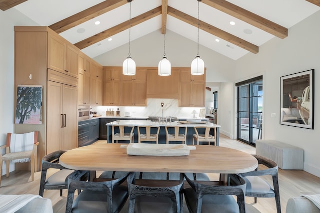 kitchen featuring beamed ceiling, hanging light fixtures, light hardwood / wood-style flooring, a center island with sink, and light brown cabinetry