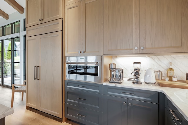 interior space with gray cabinets, light stone counters, tasteful backsplash, beam ceiling, and oven