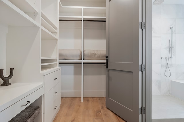 walk in closet with light hardwood / wood-style flooring