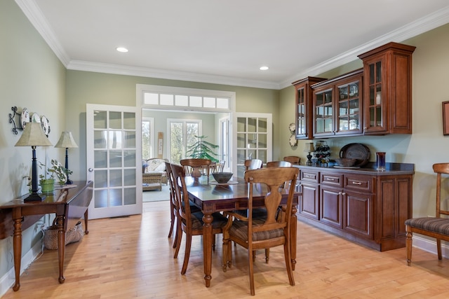 dining space with ornamental molding, light wood-type flooring, and french doors