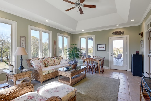 living room with ceiling fan, a raised ceiling, crown molding, and light tile patterned floors