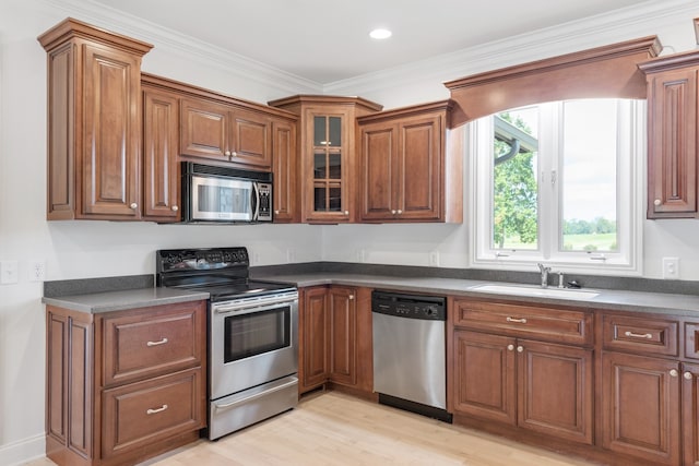 kitchen with light wood-type flooring, crown molding, sink, and stainless steel appliances