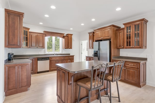 kitchen featuring white dishwasher, ornamental molding, a kitchen island, stainless steel refrigerator with ice dispenser, and light hardwood / wood-style floors