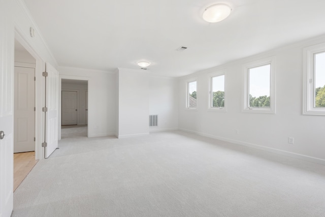 carpeted spare room featuring ornamental molding and a wealth of natural light