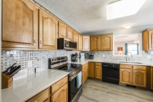 kitchen with sink, tasteful backsplash, a textured ceiling, stainless steel appliances, and light hardwood / wood-style floors