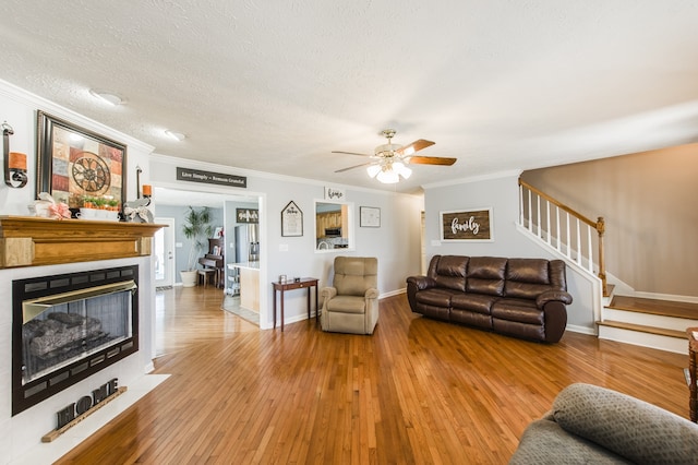 living room with a textured ceiling, crown molding, hardwood / wood-style floors, and ceiling fan