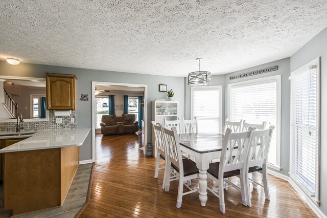 dining room featuring a notable chandelier, a wealth of natural light, a textured ceiling, and hardwood / wood-style floors