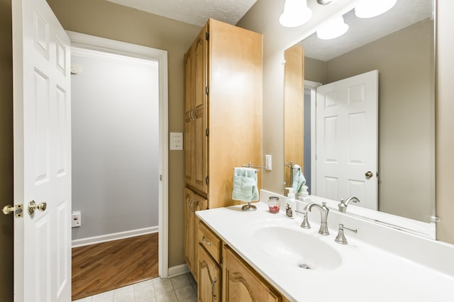 bathroom with a textured ceiling, hardwood / wood-style flooring, and vanity