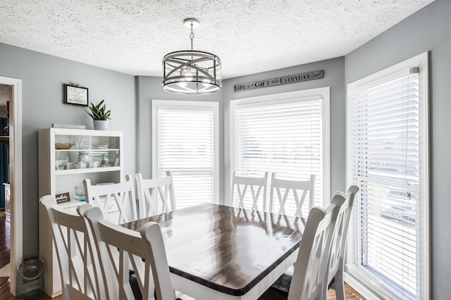 dining space featuring wood-type flooring, a notable chandelier, and a textured ceiling