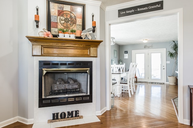 details featuring a textured ceiling, a tiled fireplace, ornamental molding, and hardwood / wood-style floors