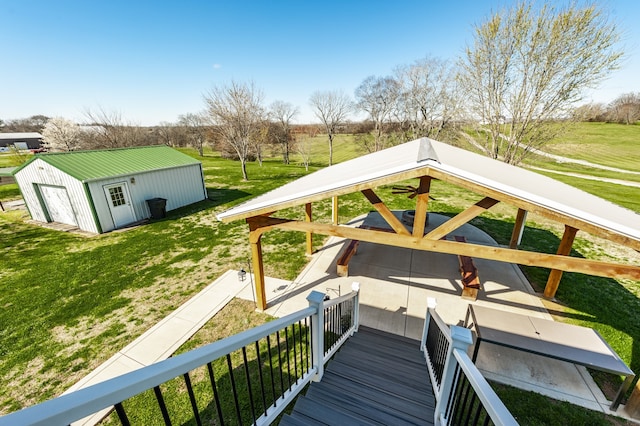 wooden terrace featuring a lawn and an outbuilding