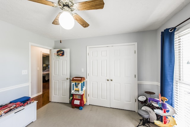 recreation room with a textured ceiling, ceiling fan, and light colored carpet