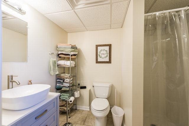 bathroom featuring vanity, a drop ceiling, tile patterned floors, walk in shower, and toilet