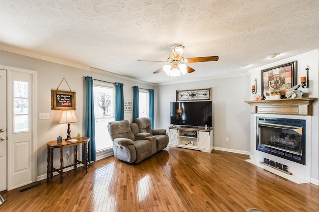 living room featuring hardwood / wood-style flooring, crown molding, a textured ceiling, and a healthy amount of sunlight