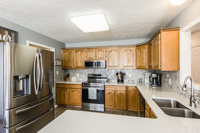 kitchen featuring a textured ceiling, dark hardwood / wood-style floors, sink, decorative backsplash, and appliances with stainless steel finishes