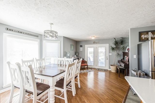 dining area featuring french doors, hardwood / wood-style flooring, a chandelier, and a textured ceiling