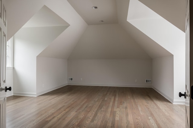 additional living space featuring vaulted ceiling and light wood-type flooring