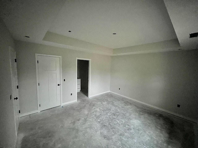 unfurnished bedroom featuring a tray ceiling and concrete floors