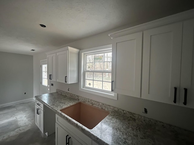 kitchen featuring sink, white cabinets, and a textured ceiling