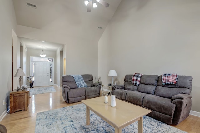 living room with light hardwood / wood-style floors, high vaulted ceiling, and ceiling fan