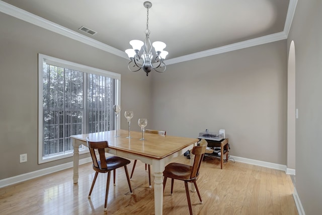 dining area featuring ornamental molding, an inviting chandelier, and light hardwood / wood-style flooring