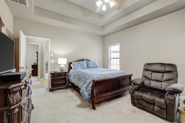 carpeted bedroom with ceiling fan and a tray ceiling