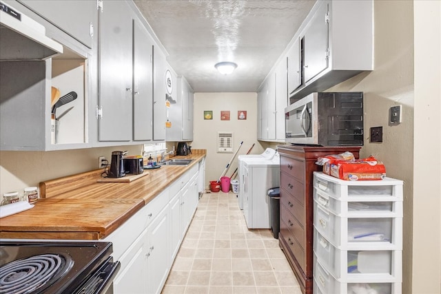 kitchen with stove, sink, white cabinets, and washer and dryer