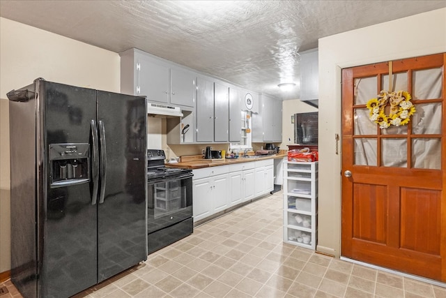 kitchen with a textured ceiling, butcher block counters, black appliances, and sink