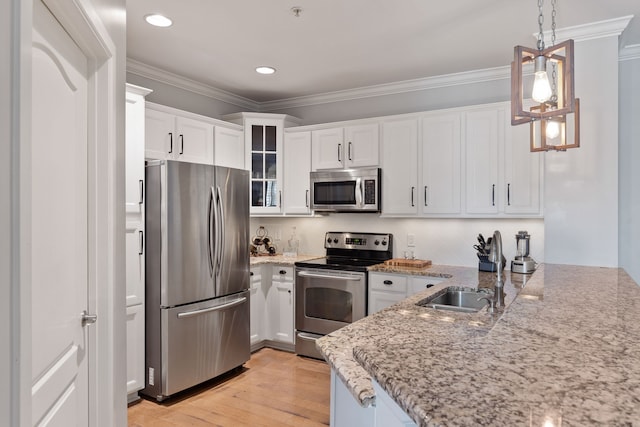 kitchen featuring hanging light fixtures, sink, white cabinetry, stainless steel appliances, and light wood-type flooring