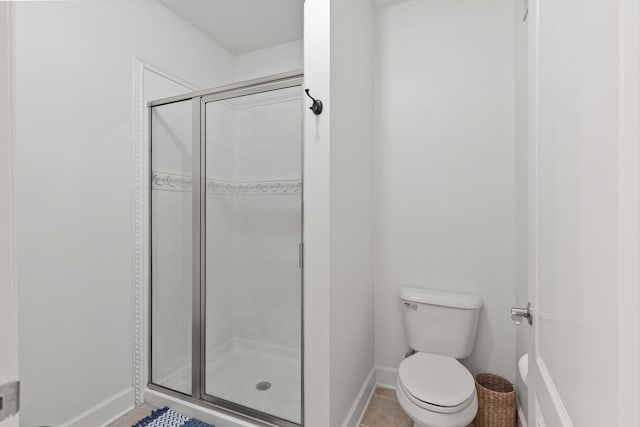 bathroom featuring tile patterned floors, a shower with shower door, and toilet