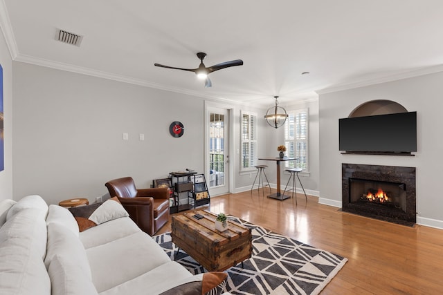 living room featuring ceiling fan with notable chandelier, crown molding, and hardwood / wood-style flooring