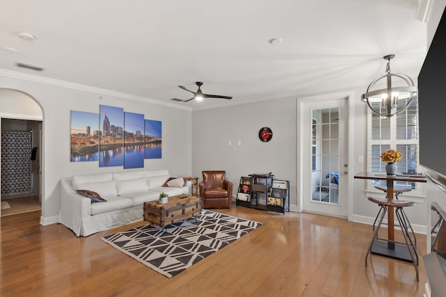 living room with ceiling fan with notable chandelier, crown molding, and wood-type flooring