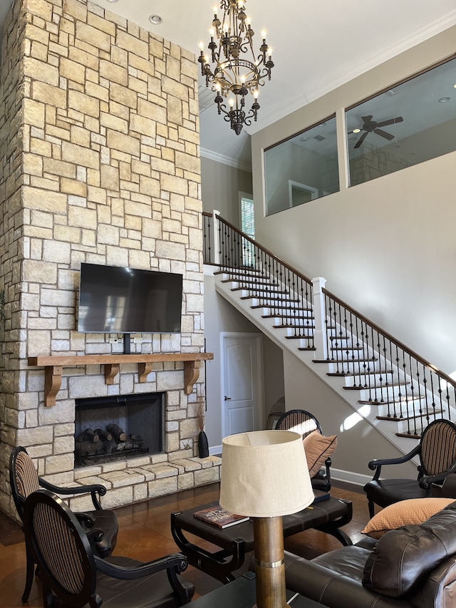 living room with a towering ceiling, crown molding, a stone fireplace, and an inviting chandelier