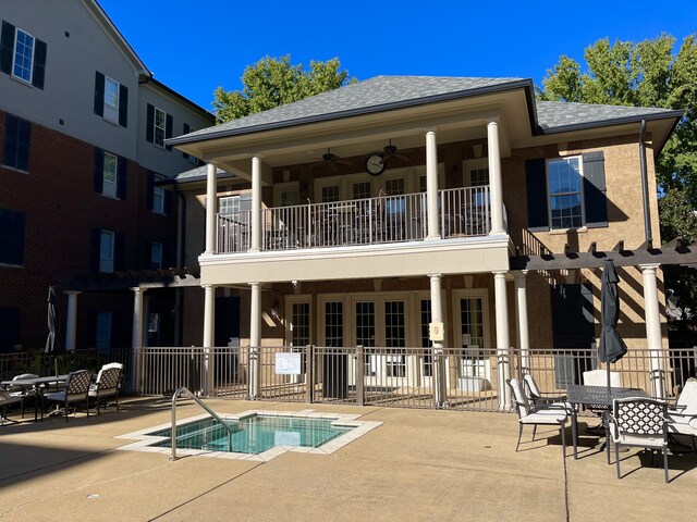 rear view of property with a balcony, a pool, and a patio area