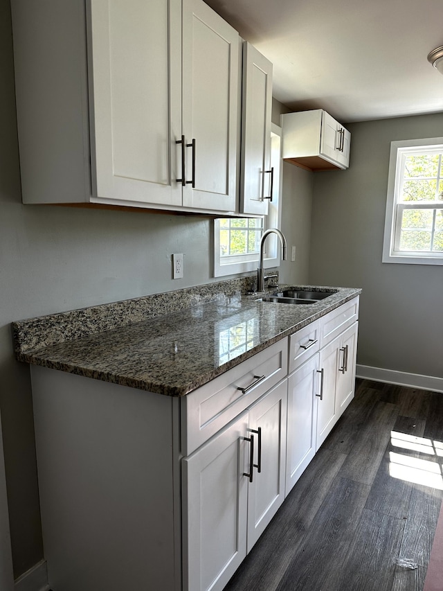 kitchen with a healthy amount of sunlight, dark stone countertops, sink, and white cabinets