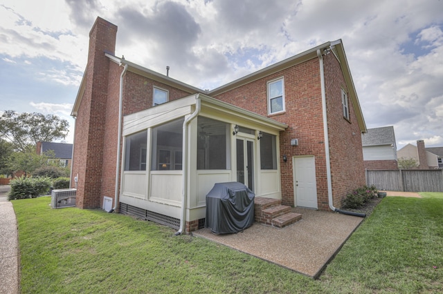 rear view of house with central air condition unit, a sunroom, and a yard